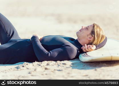 A young surfer with his board on the beach. I need some rest