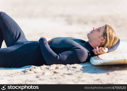 A young surfer with his board on the beach. I need some rest