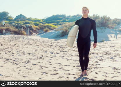 A young surfer with his board on the beach. Ready to hit waves