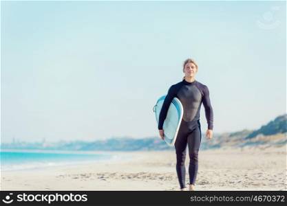 A young surfer with his board on the beach. Ready to hit waves