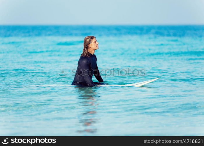 A young surfer with his board on the beach. Ready to hit waves