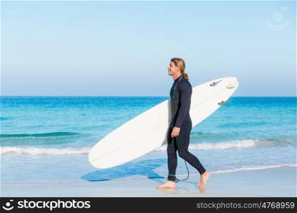 A young surfer with his board on the beach. Ready to hit waves