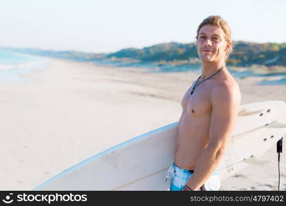 A young surfer with his board on the beach. Ready to hit waves