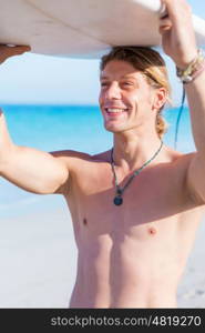 A young surfer with his board on the beach. Ready to hit waves