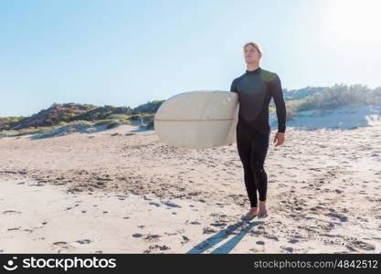 A young surfer with his board on the beach. Ready to hit waves