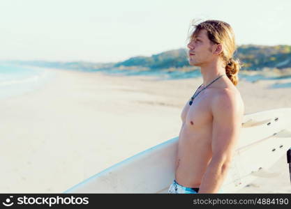 A young surfer with his board on the beach. Ready to hit waves