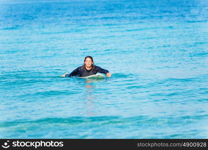 A young surfer with his board on the beach. Ready to hit waves