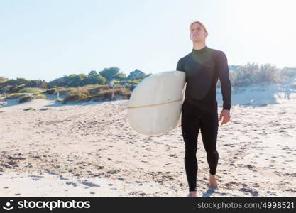 A young surfer with his board on the beach. Ready to hit waves