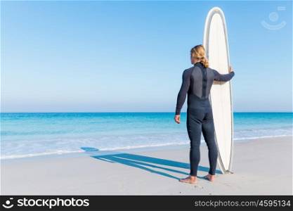 A young surfer with his board on the beach. Waitming for a perfect wave