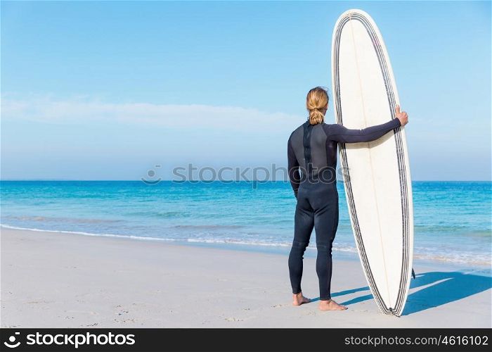 A young surfer with his board on the beach. Waitming for a perfect wave