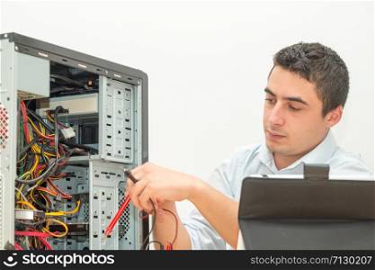 a young technician working on broken computer in his office