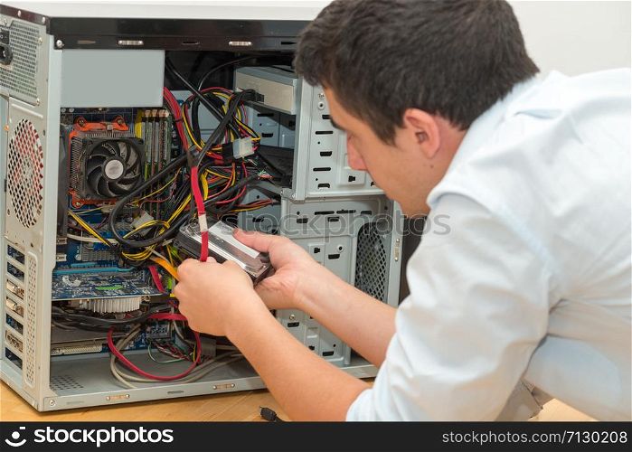 a young technician working on broken computer in his office