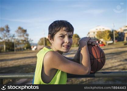 A Young teen male with sleeveless standing on a street basket court while smiling at camera. Young teen male with sleeveless standing on a street basket court while smiling at camera