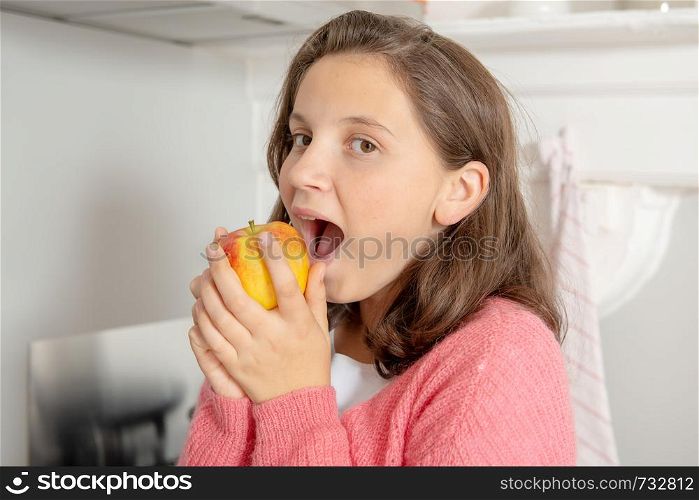 a young teenage girl eating an apple
