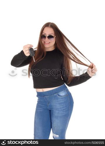 A young teenage girl got the keys for her new car holding them up, standing in jeans and black swather, isolated for white background