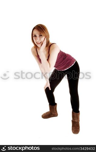 A young teenage girl in black tights and boots standing in the studio andbending forwards with her upper body, for white background.