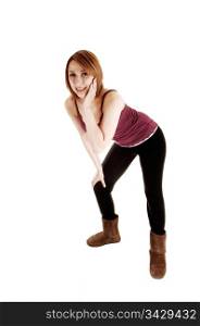 A young teenage girl in black tights and boots standing in the studio andbending forwards with her upper body, for white background.