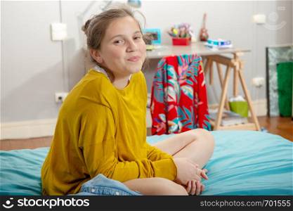 a young teenage girl sitting in cross-legs on the bed