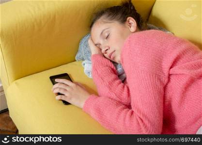 a young teenager asleep with smartphone on the sofa