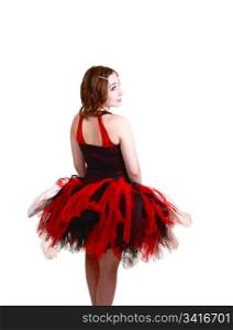 A young teenager ballerina in a red and black dress with a big twill skirtstanding from the back in the studio for white background.
