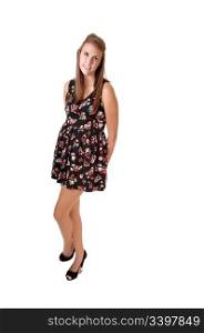 A young teenager in a black colored dress and high heels with longbrunette hair standing with grossed legs for white background.