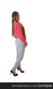 A young teenager in jeans and a red sweater and high heels standing inthe studio, with her long brunette hair, for white background.