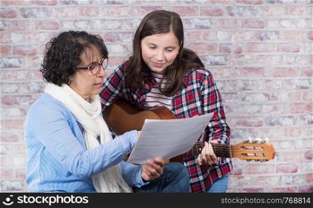 a young teenager learning to play the guitar with his teacher