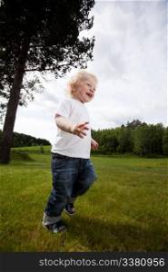 A young toddler boy running in an open grass area, excited and free