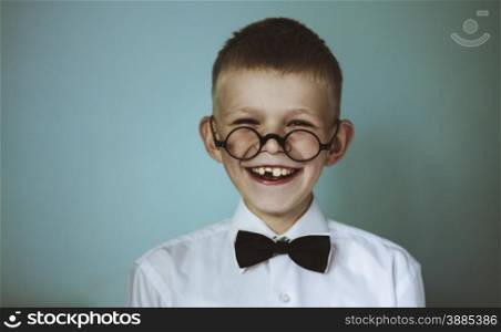 A young toothless boy wearing glasses and a black bow tie