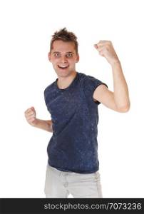 A young very happy man standing in a blue sweater and gray jeans, smiling, with his fists up into the air, isolated for white background