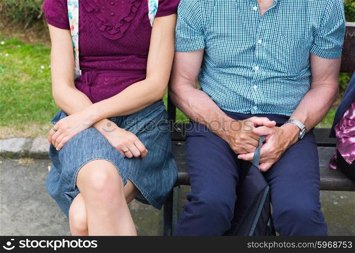 A young woman and a senior man are sitting on a bench