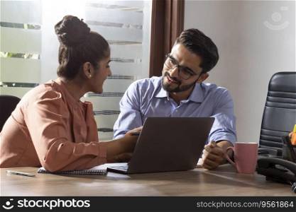 A YOUNG WOMAN AND MAN HAPPILY DISCUSSING WORK IN OFFICE
