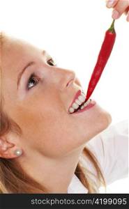 a young woman biting into a chili pepper. against a white background