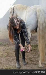 a young woman cleaning her horse's hooves