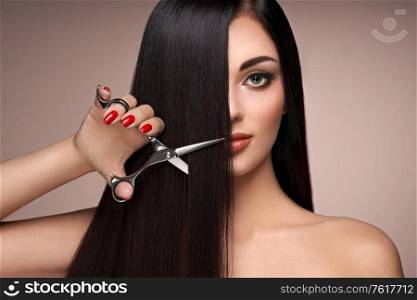 A young woman cutting her hair. Brunette model. Hair salon, hairstylist. Care and beauty hair products. Perfect make-up