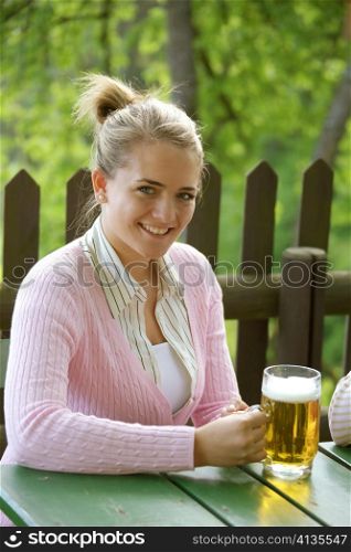 a young woman drinking a beer in the summer in a garden