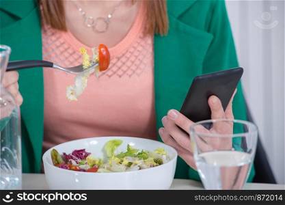 a young woman eating salad and phone