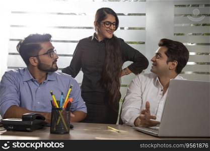 A YOUNG WOMAN EXECUTIVE DISCUSSING WORK WITH HER COLLEAGUES
