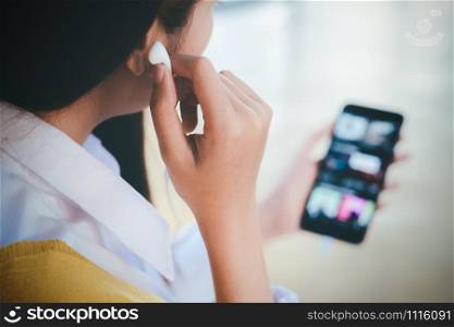 A young woman feel relaxed and listen to online music from mobile phone in her house.