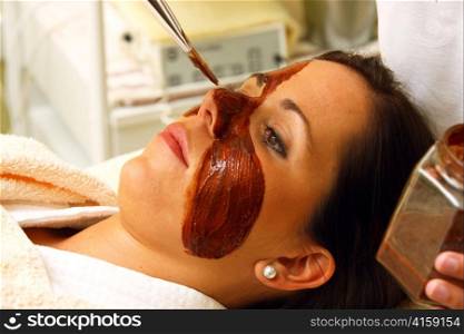 a young woman gets a chocolate mask in the beauty salon.