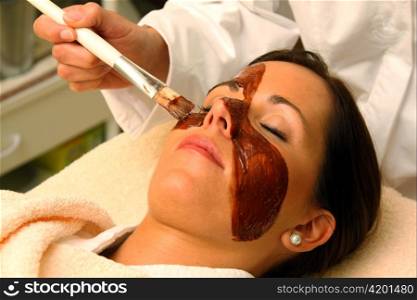 a young woman gets a chocolate mask in the beauty salon.