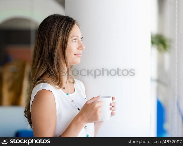 A young woman having coffee in office
