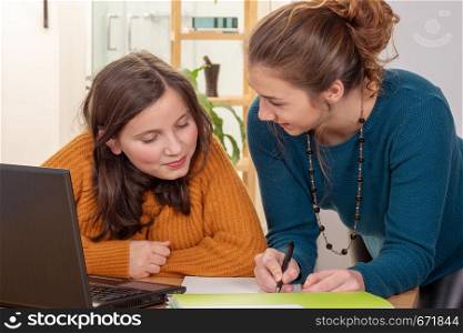 a young woman helps a teen girl with homework