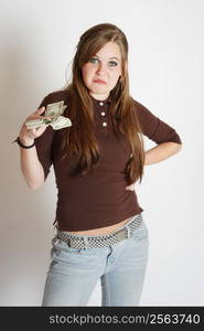 A young woman holds some money while having a disgusted look on her face