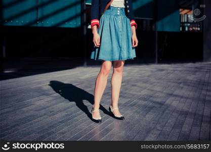 A young woman in a 1930&rsquo;s inspired outfit is standing in the street on a sunny day