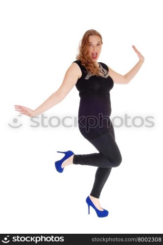 A young woman in a black sweater and tights, in blue high heels with curly blond hair dancing, isolated for white background.