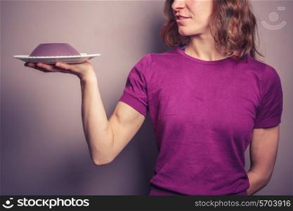 A young woman in a purple top is presenting a plate of jelly