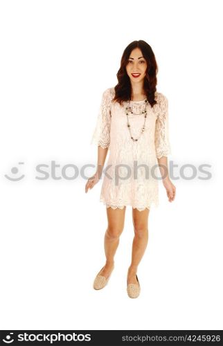 A young woman in a short beige dress standing from the front in fulllengths for white background in the studio.