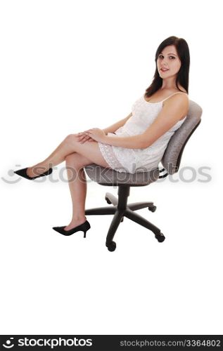 A young woman in a white lace dress sitting on a office chair, white highheels and smiling into the camera, for white background.