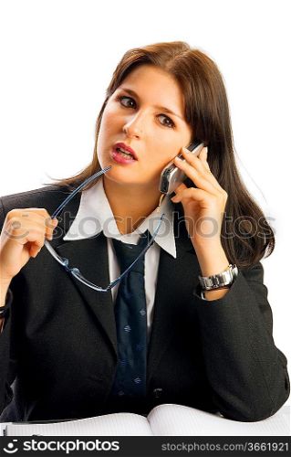 a young woman in black jacket and white shirt and a tie sitting down behind an office table and talking by phone